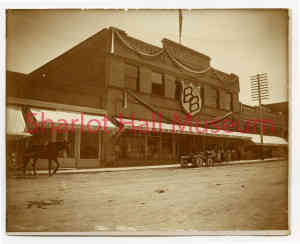 Antique sepia photograph of brick storefront with white awnings
